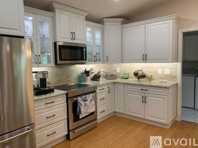 A kitchen with white cabinets and a stainless steel refrigerator.