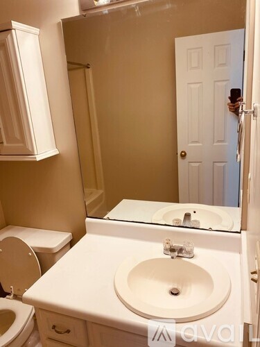 A white bathroom with a toilet, sink and mirror.