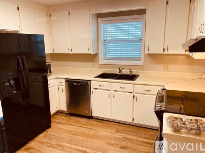 A kitchen with white cabinets and a black refrigerator.