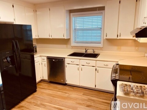 A kitchen with white cabinets and a black refrigerator.