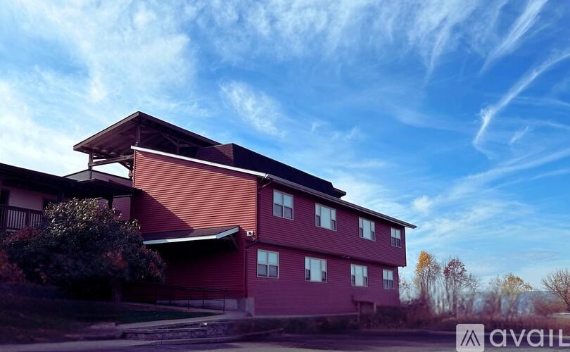 A red building with a balcony and a sign that says "available" in the foreground.