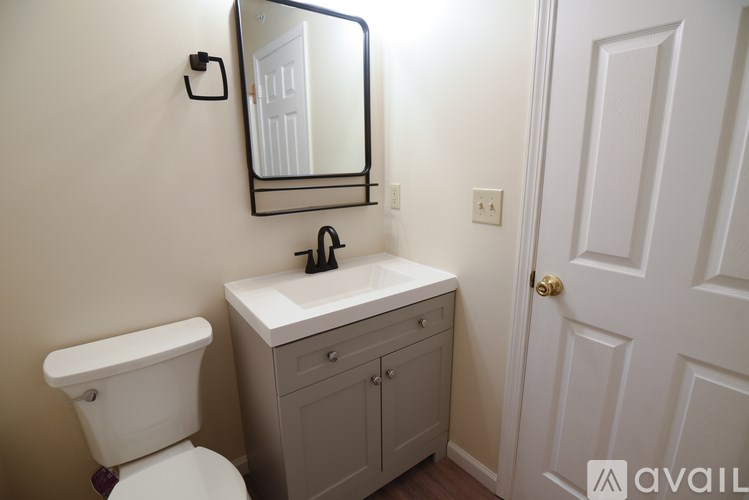 A bathroom with a toilet, sink, and mirror.