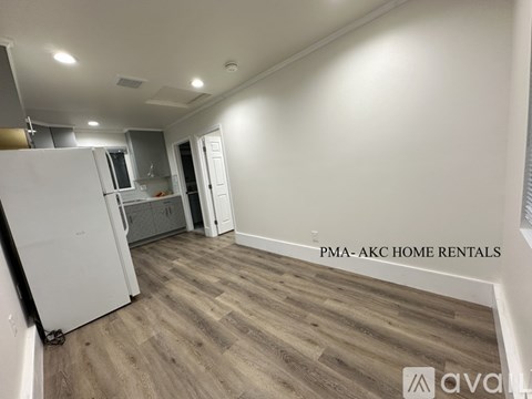 A kitchen area with a white refrigerator and wooden flooring.