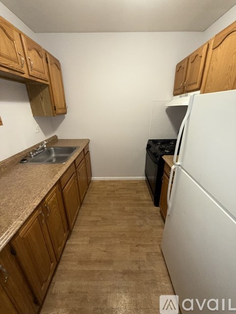 A kitchen with wooden cabinets and a white fridge.