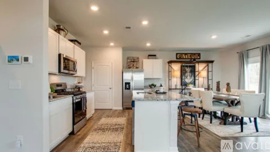 A kitchen with white cabinets and a white island with a bar.