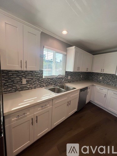 A kitchen with white cabinets and a black and white tiled backsplash.