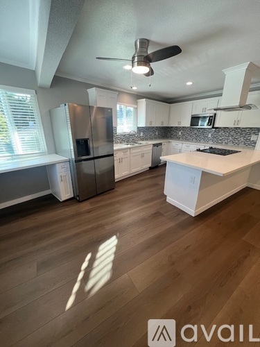 A kitchen with a refrigerator, microwave, and a fan.