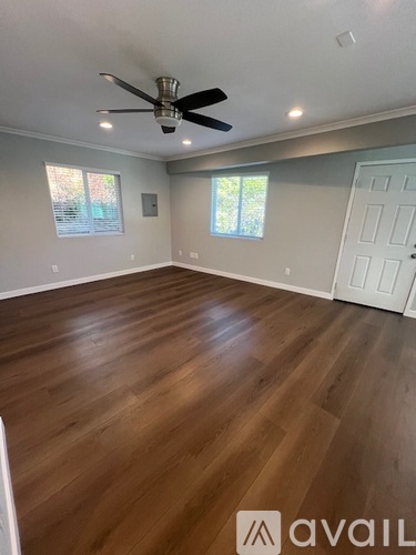 A room with a ceiling fan and wooden flooring.