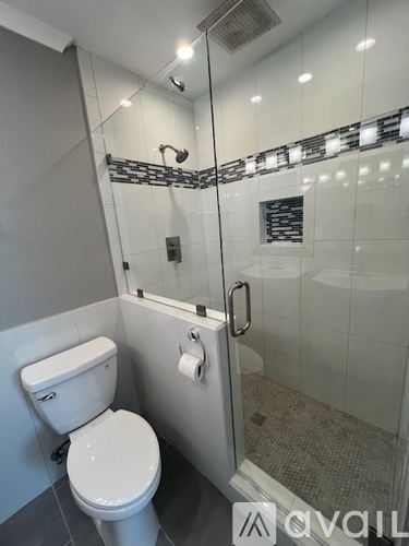 A white toilet in a modern bathroom with a glass shower stall.