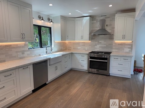 A kitchen with white cabinets and a wooden floor.