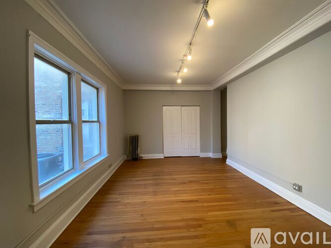 A room with wooden floors and a window overlooking a street.