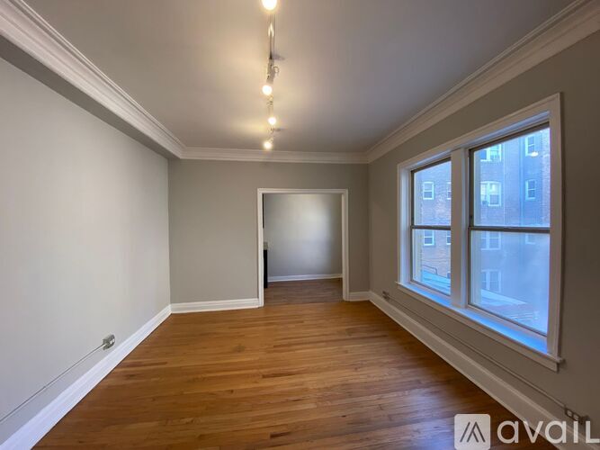 A room with wooden floors and a large window on the right side.
