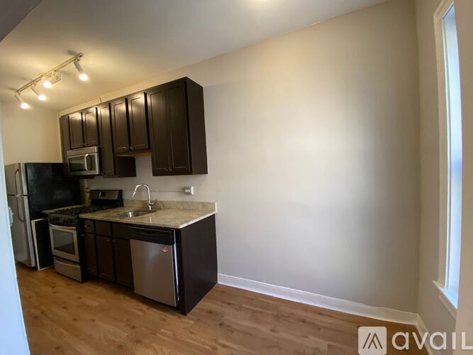 A kitchen with dark brown cabinets and a granite countertop.