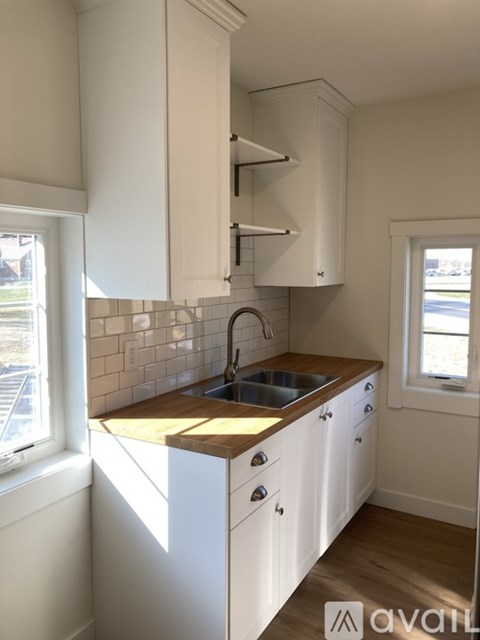 A kitchen with white cabinets and a wooden countertop.