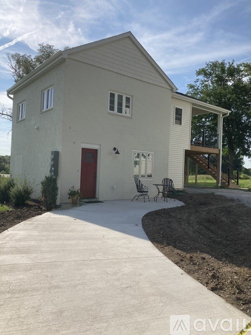 A white house with a red door and a patio area.