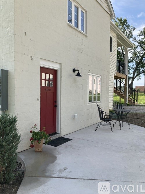 A white house with a red door and a small patio area.