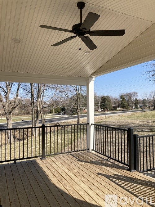 A deck with a ceiling fan and a view of a grassy area.