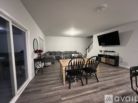A living room with a wooden floor and a television mounted on the wall.
