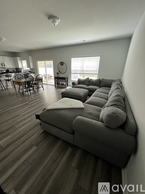 A living room with a grey couch and wooden flooring.