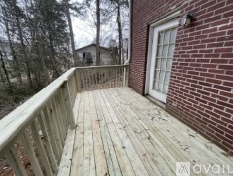 A wooden deck with a brick building and trees in the background.