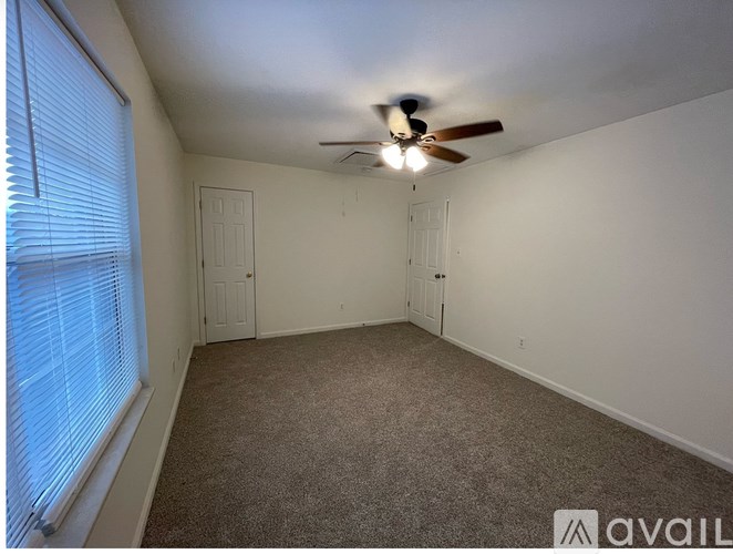 A room with a ceiling fan and carpeted floor.