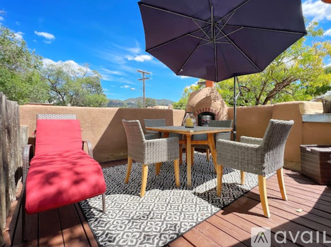 A patio with a table, chairs and an umbrella.