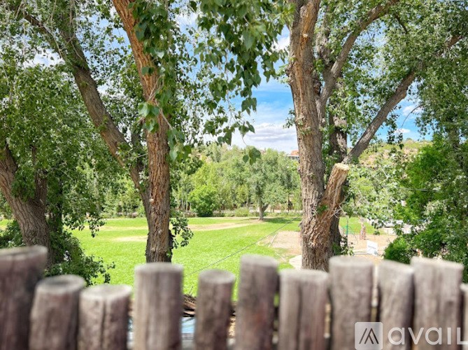 A wooden fence in front of a grassy area with trees.