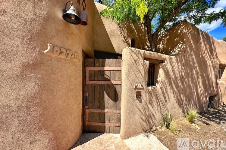 A building with a brown door and windows with a tree in the background.