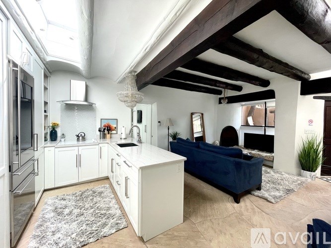 A modern kitchen with white cabinets and a blue sofa.