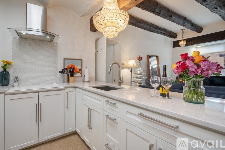 A kitchen with white cabinets and a wooden beam ceiling.