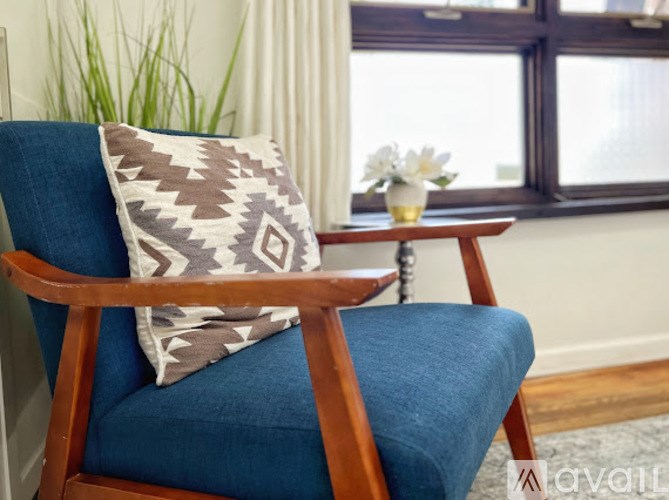 A wooden chair with a blue cushion and a brown and white pillow.