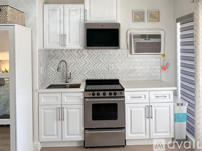A kitchen with white cabinets and a black stove top oven.