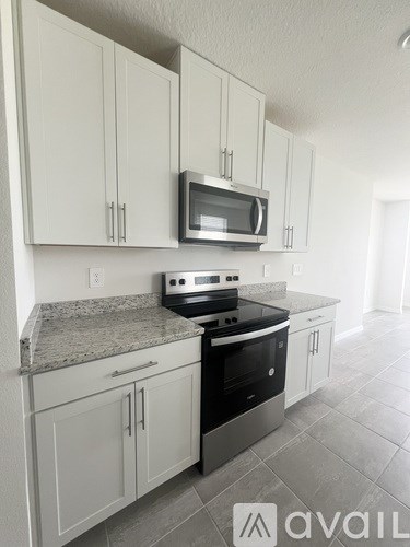 A kitchen with white cabinets and a granite countertop.