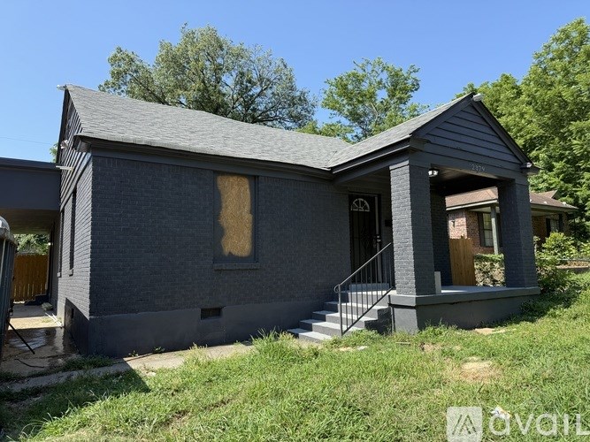 A grey house with a boarded up window.