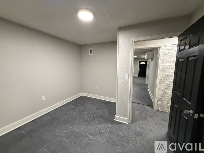 A room with a black door and a grey floor.