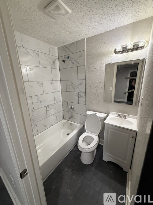 A white toilet sits in a bathroom with a white tub and sink.