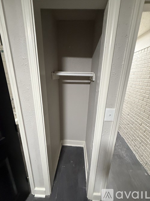 A small white closet with a shelf and a black door.