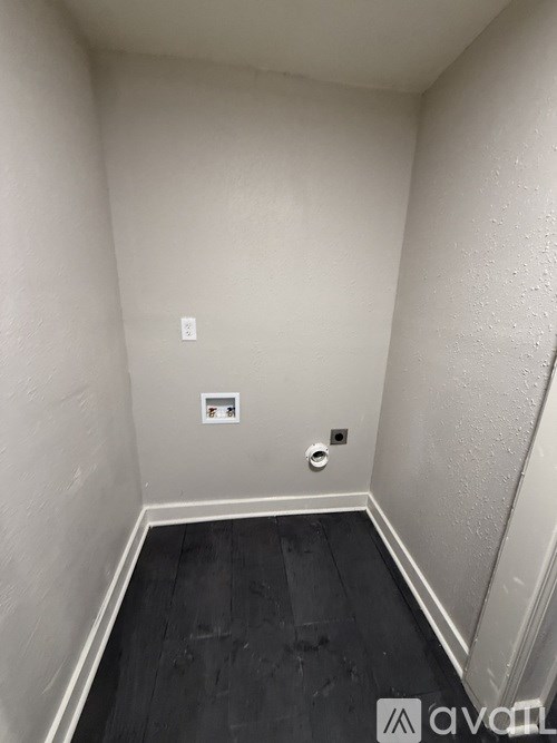 A small, empty room with a wooden floor and white walls.