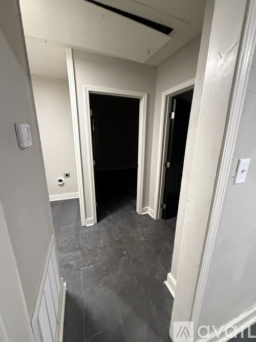A hallway with two doors and a wall-mounted thermostat.