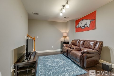 A living room with a brown leather couch and a red pig picture on the wall.
