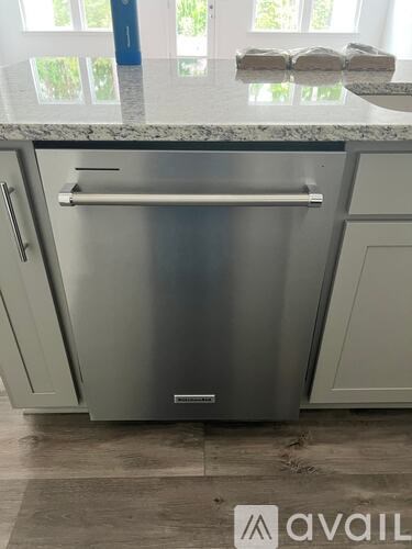A stainless steel refrigerator with a handle and a drawer is in a kitchen.