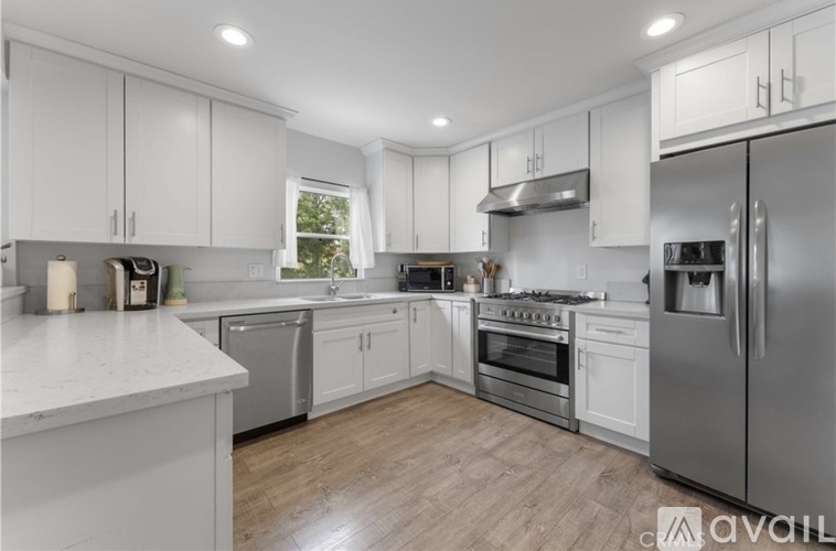 A modern kitchen with white cabinets and stainless steel appliances.