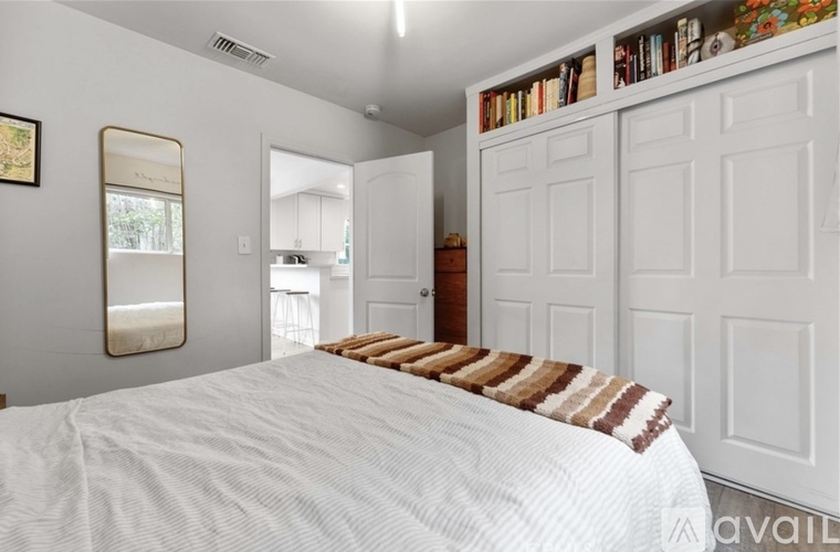 A bedroom with a large bed and a bookshelf filled with books.