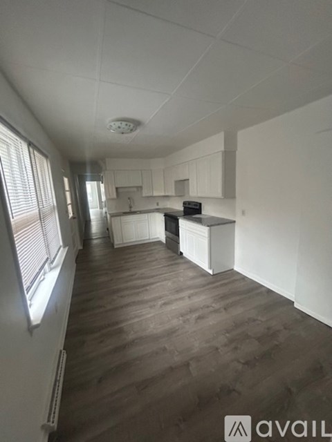 A kitchen area with white cabinets and a wooden floor.