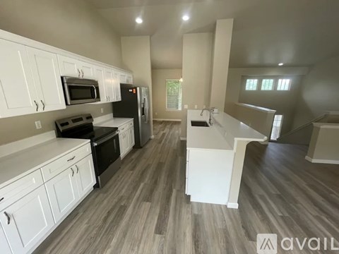 A kitchen with white cabinets and a grey floor.