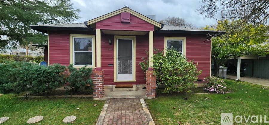 A red house with a white door and a brick walkway leading to the front door.