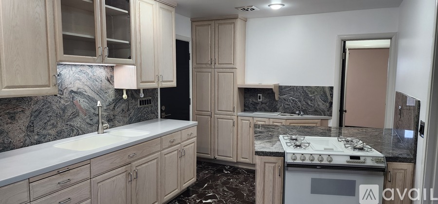 A kitchen with wooden cabinets and a marble countertop.