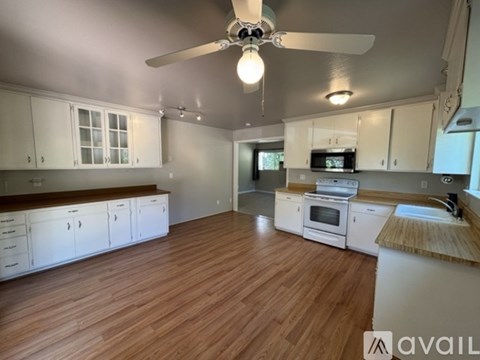 A kitchen with white cabinets and a wooden floor.