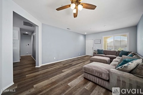 A living room with a couch and a ceiling fan.