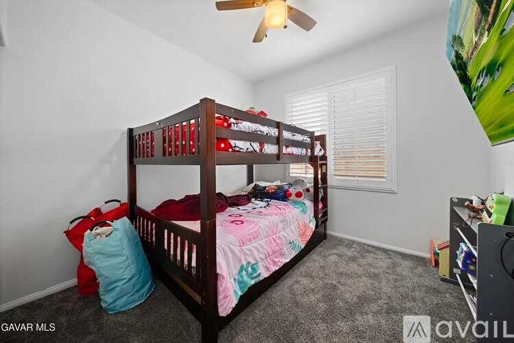 A bedroom with a bunk bed and a ceiling fan.